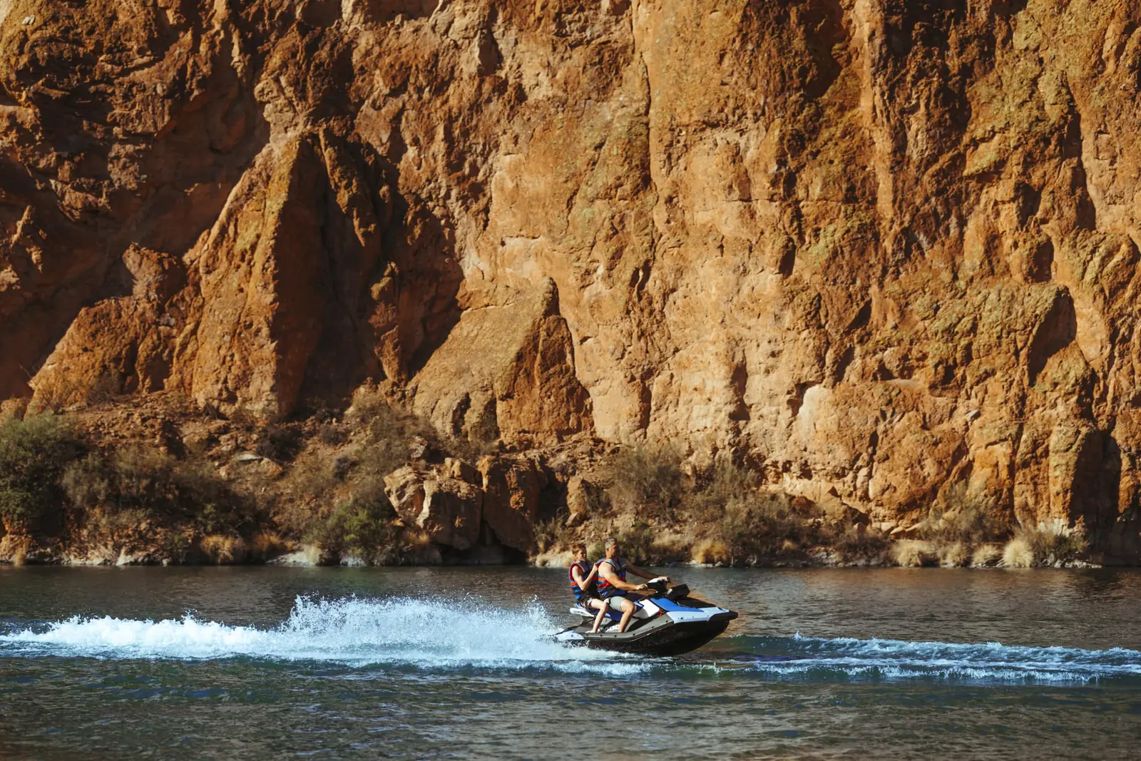 Lone jet ski dwarfed by the desert canyon wall on an Arizona lake